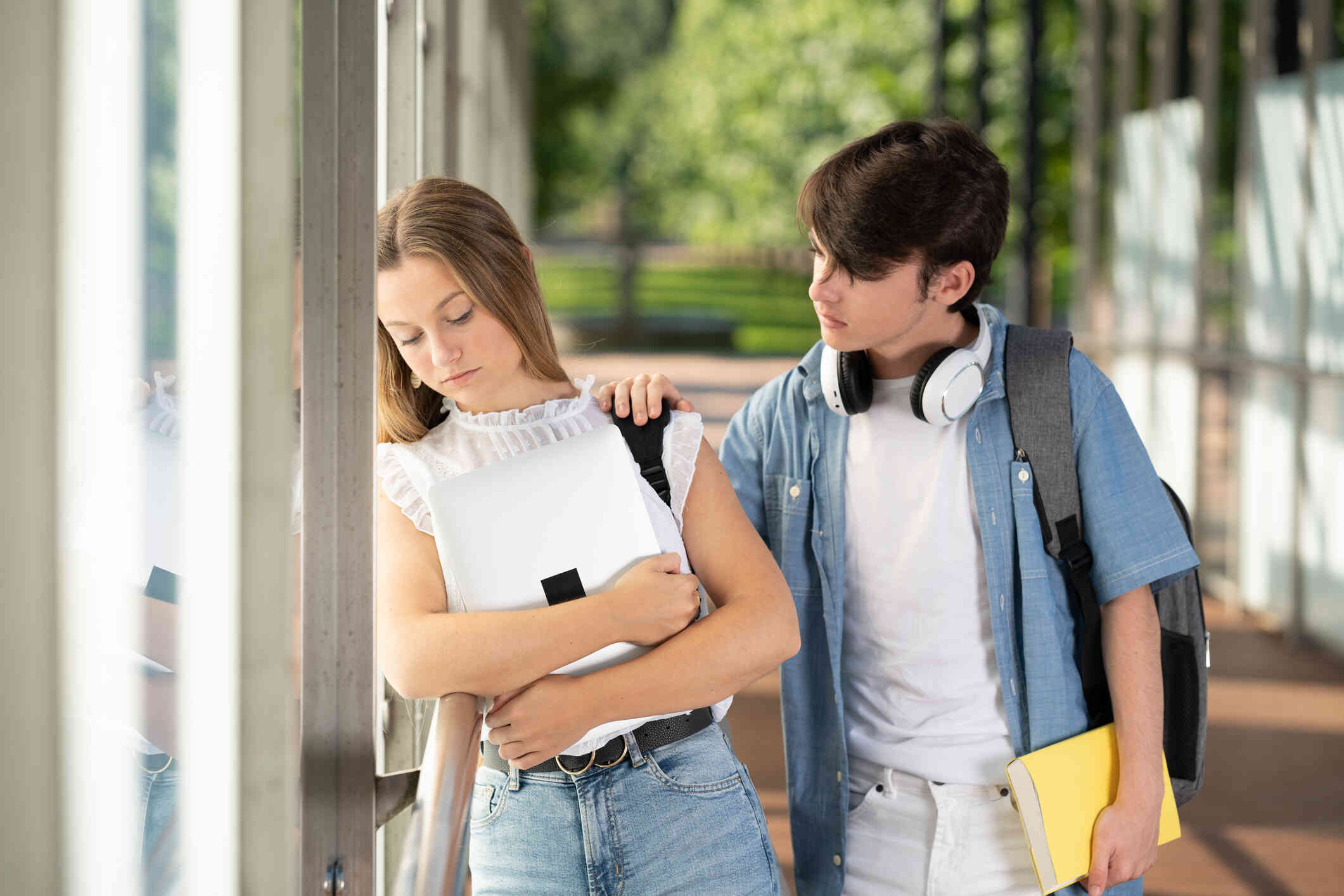 A teenager girl appears down, while the boy holds her shoulder showing concern.